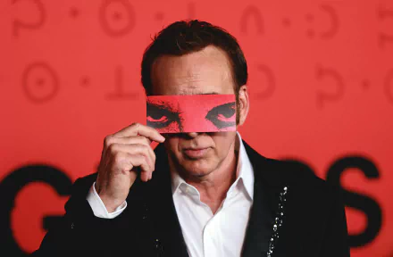 HD desktop wallpaper featuring a man holding a red card with eyes printed on it against a red background, tagged with movie and Longlegs.