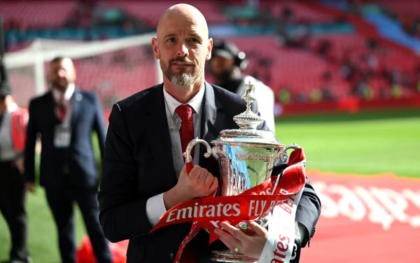 A man holding a trophy in a soccer stadium, tagged with Sports, soccer, Manchester United F.C. This HD desktop wallpaper and background captures a moment of victory.