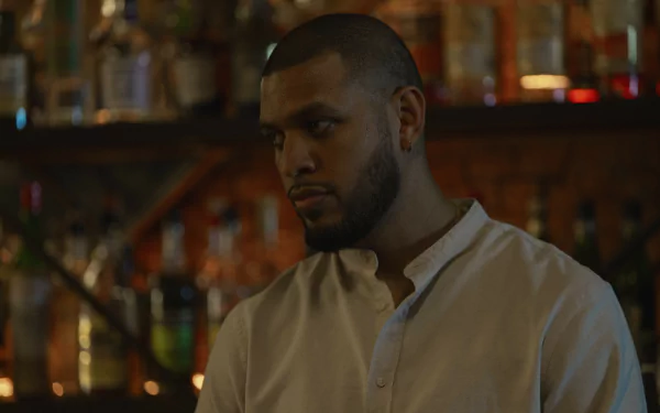 A HD desktop wallpaper featuring a scene from the TV Show Presumed Innocent (2024) with a man standing in a dimly-lit bar.