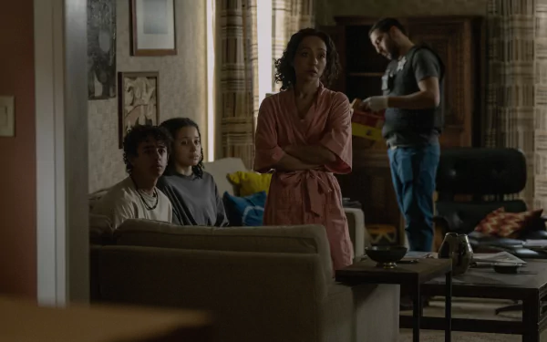 HD wallpaper from the TV show Presumed Innocent (2024) depicting a tense indoor scene with three people seated and one person standing in a living room.