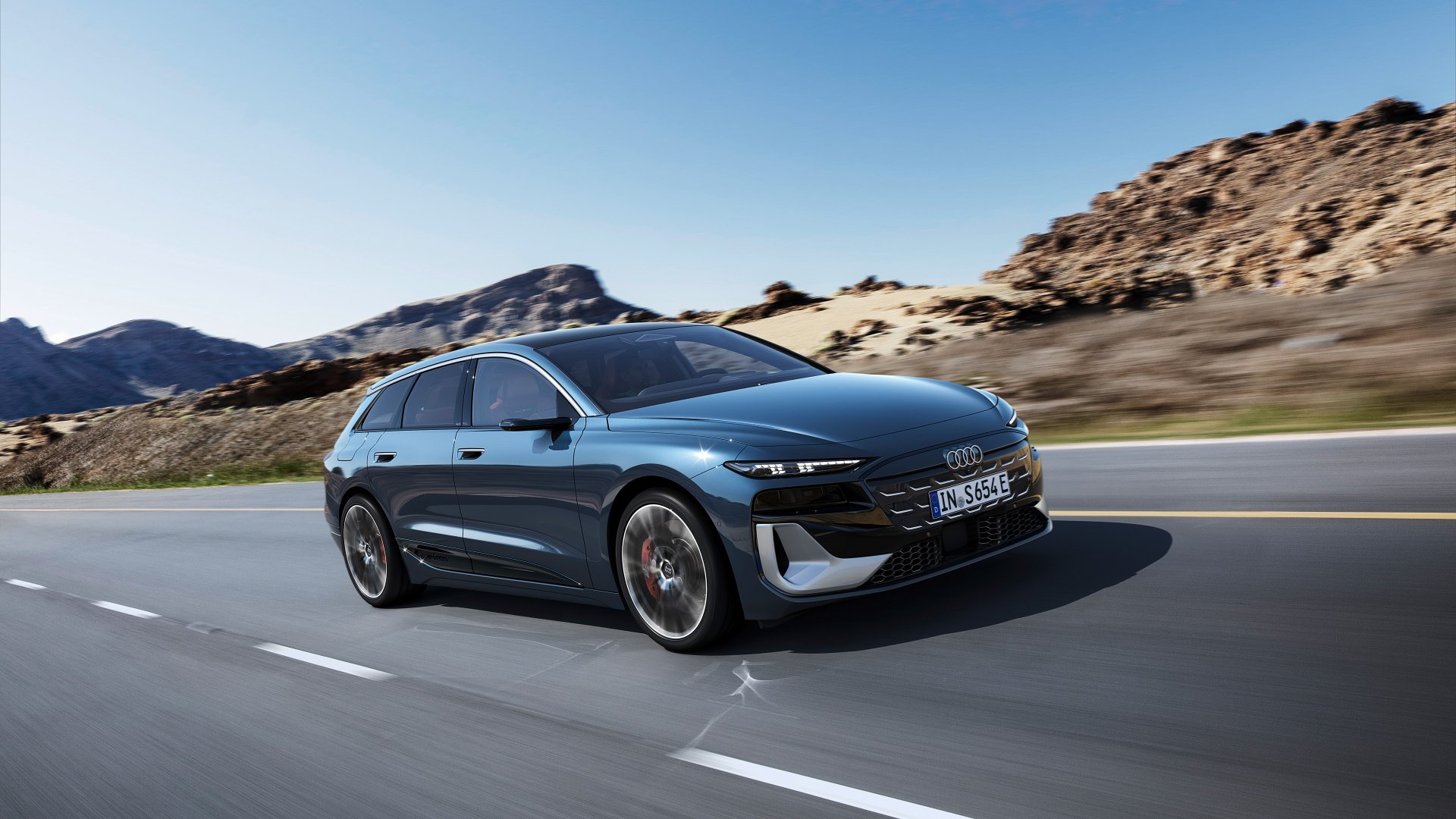 A sleek Audi S6 E-Tron drives along a winding road, framed by rugged mountains. This stunning image serves as an HD desktop wallpaper and background for car enthusiasts.