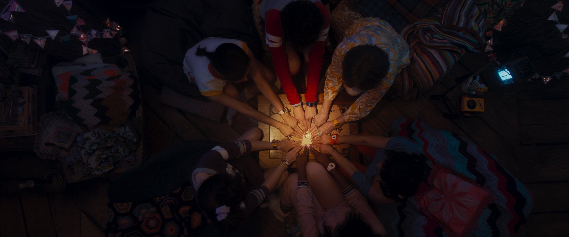 A captivating HD wallpaper featuring a group of individuals gathered around a glowing light, creating an enchanting atmosphere reminiscent of the TV show Agatha All Along.