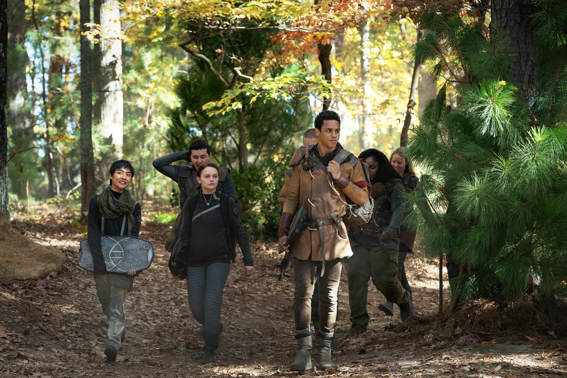 A group of young people walks through a forest, showcasing themes of rebellion and friendship from the movie Uglies. The scene captures the essence of adventure in vibrant autumn colors.