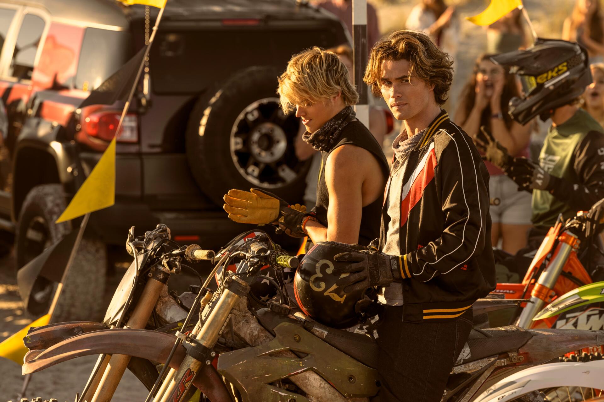 Chase Stokes and Rudy Pankow from the TV show Outer Banks pose on motorcycles, capturing a vibrant scene from the series in this HD desktop wallpaper.