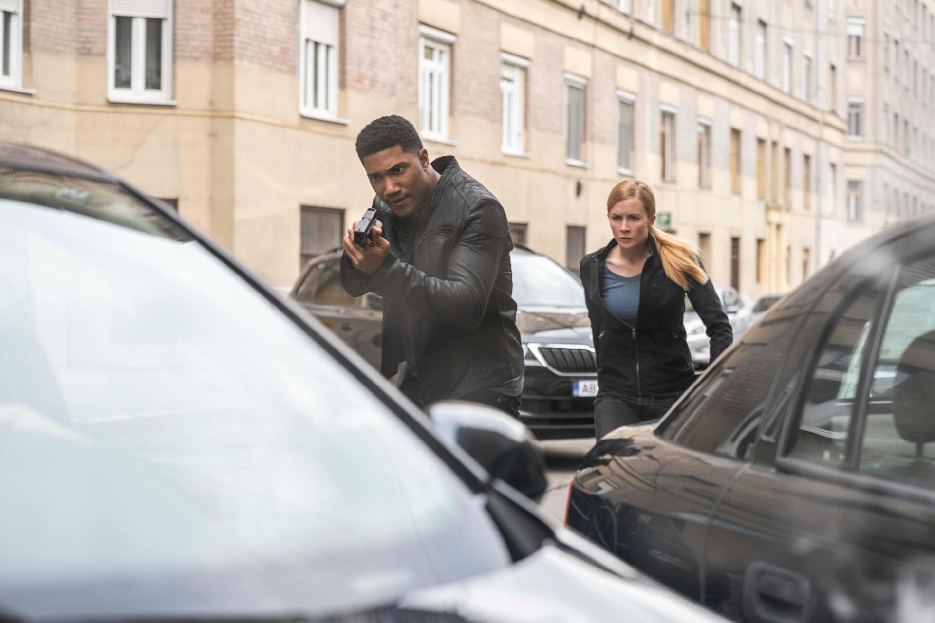 A tense moment from the TV show FBI: International, featuring agents navigating a city street, showcasing action and drama in a 4K Ultra HD desktop wallpaper.