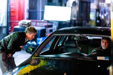 A dramatic scene from the movie Wolfs (2024) featuring George Clooney and Brad Pitt, set against a nighttime urban backdrop, showcasing tension and intrigue.