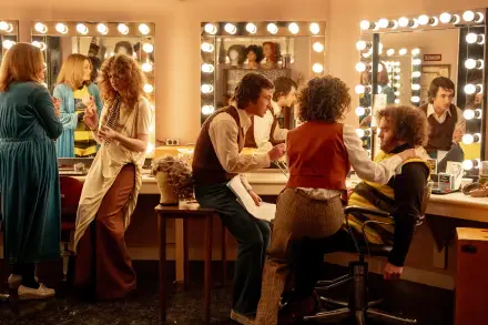 A lively scene from the movie Saturday Night, showcasing actors in a bustling dressing room, complete with mirrors and bright lights, captured in stunning 4K Ultra HD.