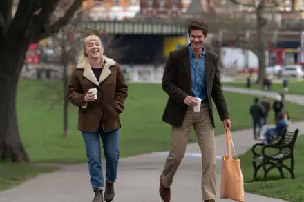 A vibrant HD wallpaper from the movie We Live in Time, featuring Andrew Garfield and Florence Pugh enjoying a joyful walk in a park.