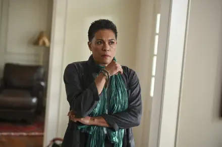 A dramatic scene from the TV show Tracker (2024), featuring a woman with a concerned expression, wearing a green scarf, set in a stylish indoor environment. HD wallpaper background.