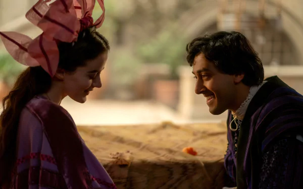 A scene from the TV show The Decameron, featuring two characters in vibrant costumes sharing a moment, set against a soft, blurred background. This makes a captivating HD desktop wallpaper.