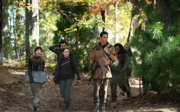A group of young people walks through a forest, showcasing themes of rebellion and friendship from the movie Uglies. The scene captures the essence of adventure in vibrant autumn colors.