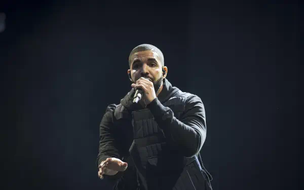 A dynamic HD wallpaper featuring rapper Drake performing passionately on stage, capturing the energy of live music and the essence of his artistry.