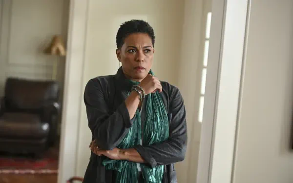 A dramatic scene from the TV show Tracker (2024), featuring a woman with a concerned expression, wearing a green scarf, set in a stylish indoor environment. HD wallpaper background.