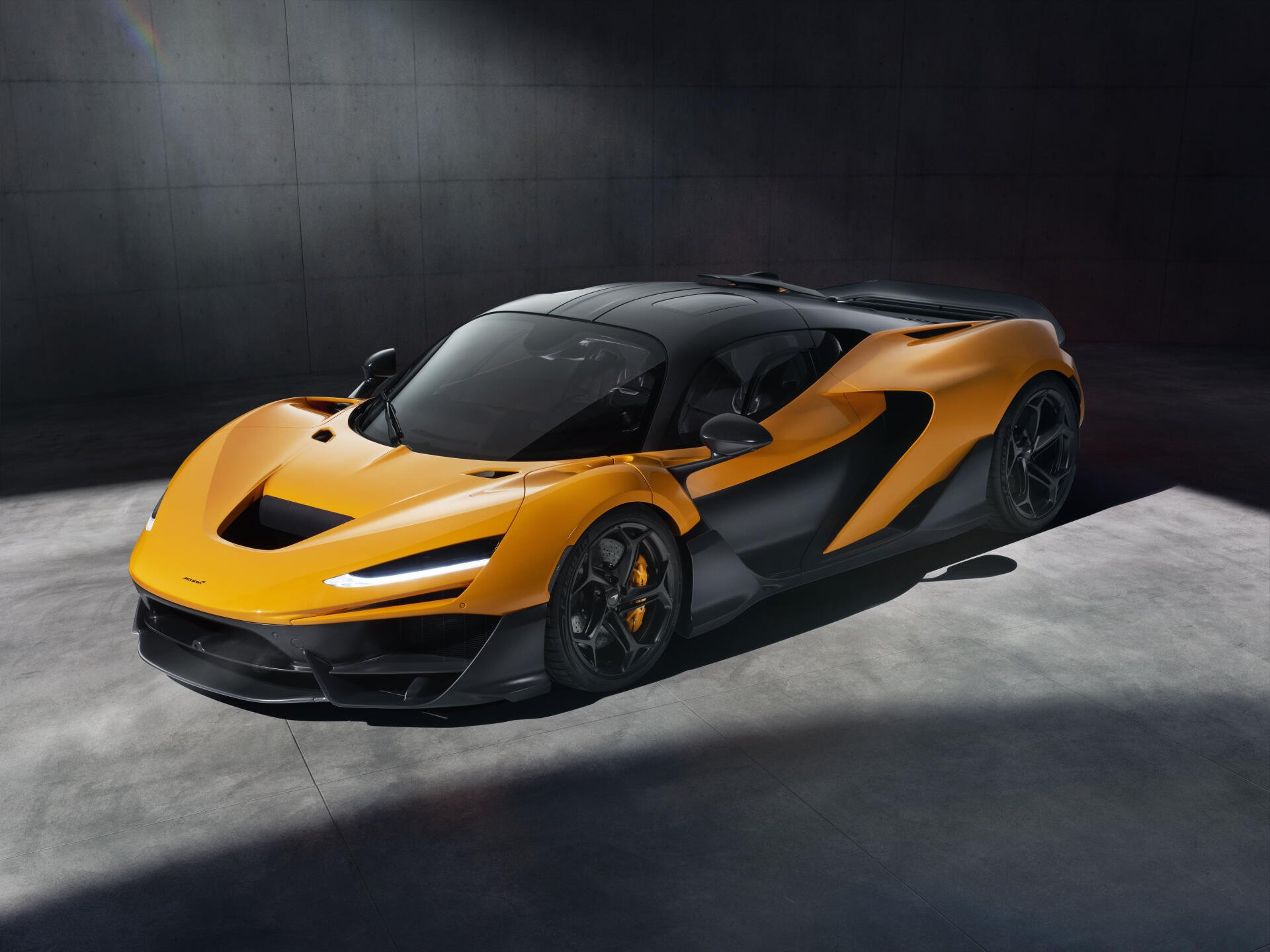 A striking McLaren W1 in vibrant orange and black, showcasing its aerodynamic design against a minimalist backdrop. This 8K Ultra HD image makes a bold statement for any desktop.