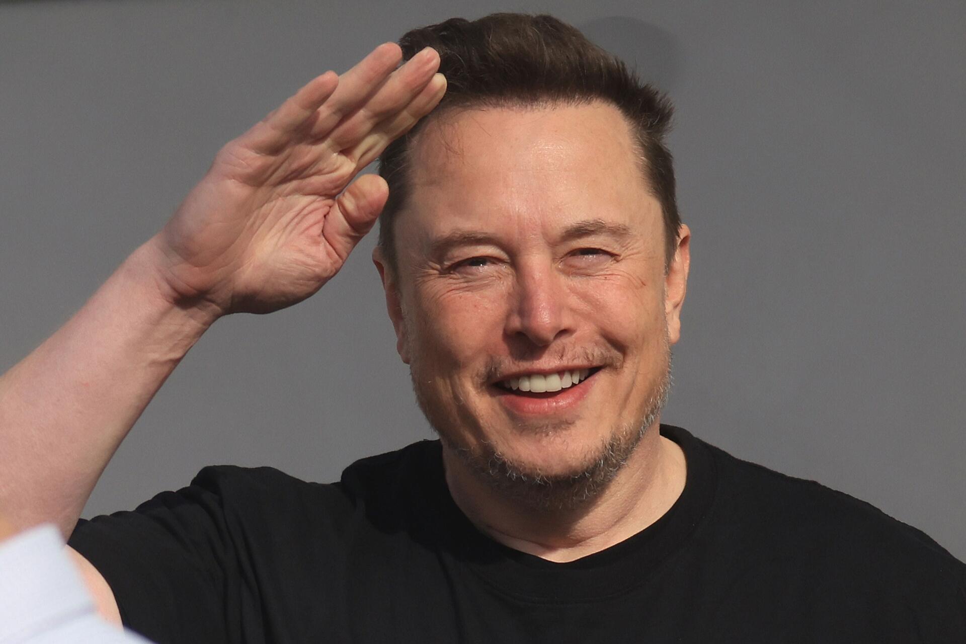 Elon Musk smiling and saluting, captured in a vibrant 4K Ultra HD backdrop, showcasing his personality and charisma as a prominent celebrity in the tech world.