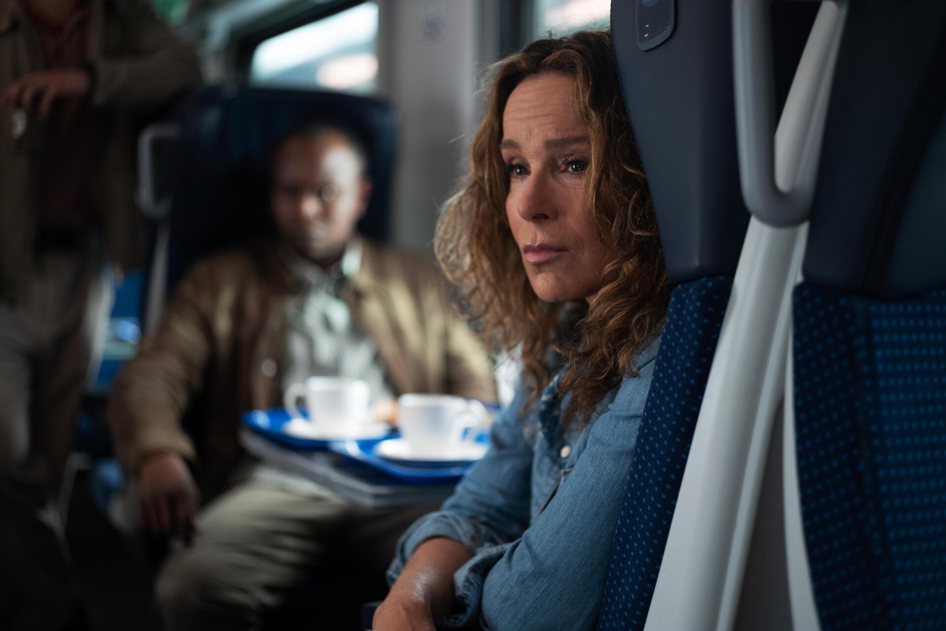 A scene from the movie A Real Pain, featuring a woman with curly hair gazing thoughtfully while seated on a train, captured in a striking 4K Ultra HD desktop wallpaper.