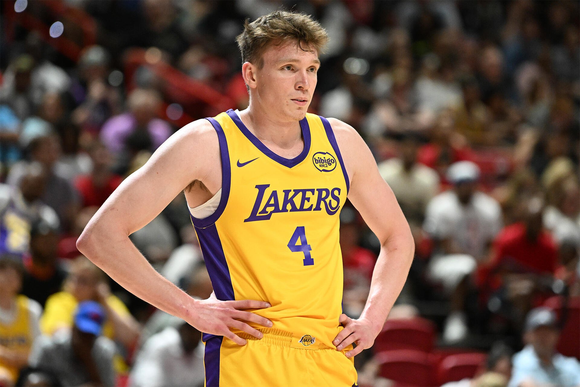 Dalton Knecht of the Los Angeles Lakers stands on the court, wearing his yellow and purple uniform, during a basketball game amidst a lively crowd.