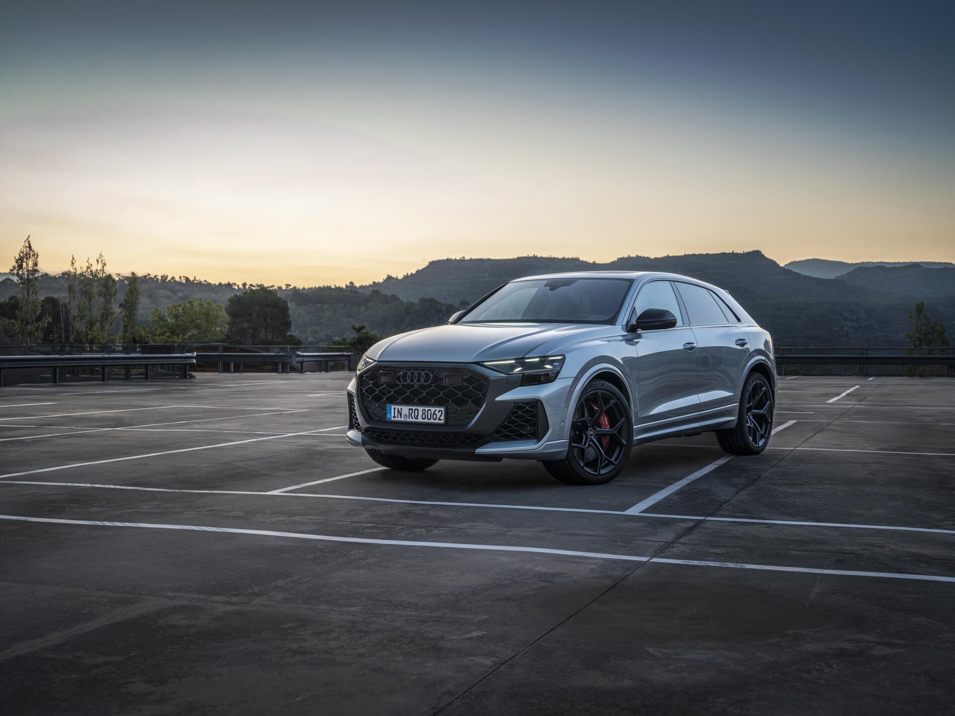 An Audi RS Q8 parked in an empty lot at dusk, showcasing its sleek design and sporty details, set against a backdrop of hills. A striking 4K Ultra HD desktop wallpaper.