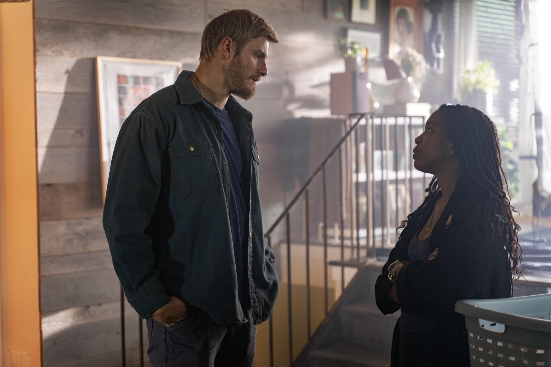 A scene from the TV show Earth Abides featuring Alexander Ludwig and Jessica Frances Dukes in a dramatic conversation, set against a rustic background. HD wallpaper for desktop use.