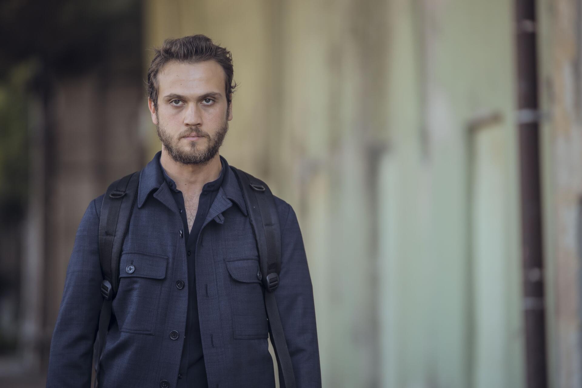 A character from the TV show The Pit is captured in a contemplative moment, standing confidently with a backpack against an urban background. This stunning 4K Ultra HD wallpaper showcases intense detail.
