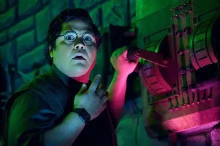Harvey Guillén as Guillermo in a vibrant scene from What We Do in the Shadows, showcasing his expressive reaction against a colorful, moody backdrop. HD wallpaper for fans.