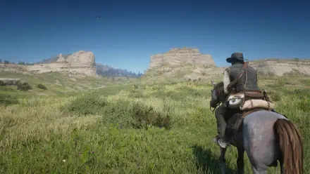 A serene landscape from *Red Dead Redemption 2*, showcasing a character on horseback, surrounded by lush greenery and rocky formations under a clear blue sky. Ideal HD wallpaper for gamers.
