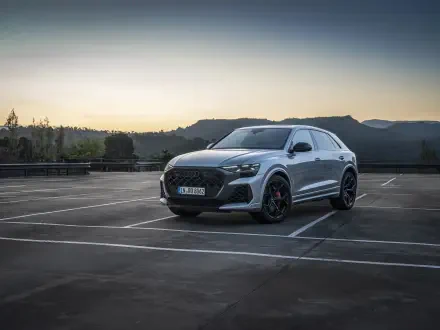An Audi RS Q8 parked in an empty lot at dusk, showcasing its sleek design and sporty details, set against a backdrop of hills. A striking 4K Ultra HD desktop wallpaper.