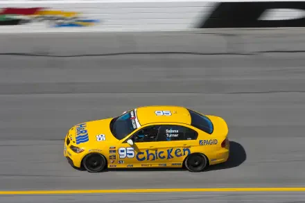 A vibrant yellow BMW E90 race car with 95 and Chicken branding speeds around a track, showcased as a high-definition PC desktop wallpaper and background.