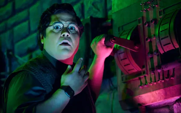 Harvey Guillén as Guillermo in a vibrant scene from What We Do in the Shadows, showcasing his expressive reaction against a colorful, moody backdrop. HD wallpaper for fans.