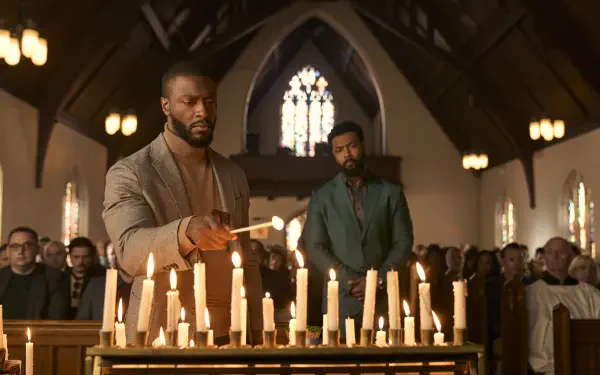 Aldis Hodge and Isaiah Mustafa in a poignant scene from the TV show Cross (2024), set in a candlelit church filled with attendees. An evocative backdrop for your desktop.