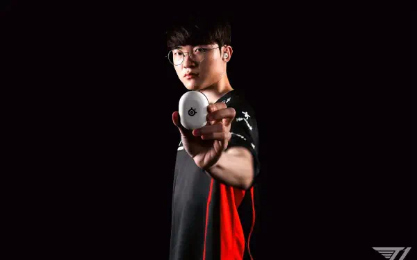 A high-definition esports wallpaper featuring T1's Faker, a prominent League of Legends player, gripping a gaming mouse against a dark background.