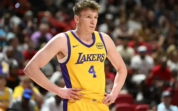 Dalton Knecht of the Los Angeles Lakers stands on the court, wearing his yellow and purple uniform, during a basketball game amidst a lively crowd.