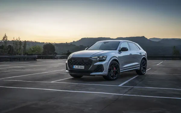 An Audi RS Q8 parked in an empty lot at dusk, showcasing its sleek design and sporty details, set against a backdrop of hills. A striking 4K Ultra HD desktop wallpaper.