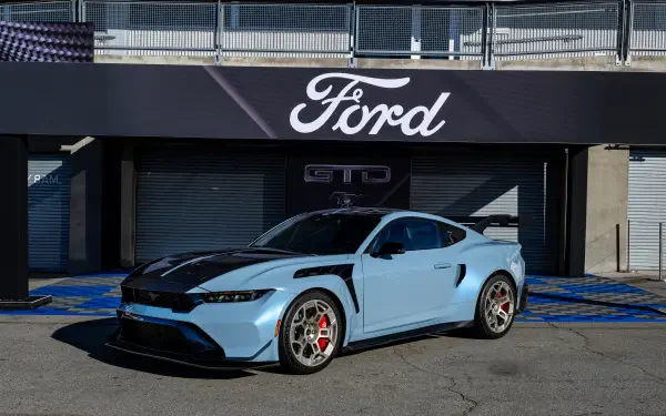 A sleek blue Ford Mustang GTD parked in front of a Ford sign, showcasing its modern design in a vibrant 4K Ultra HD backdrop. Ideal as a desktop wallpaper.