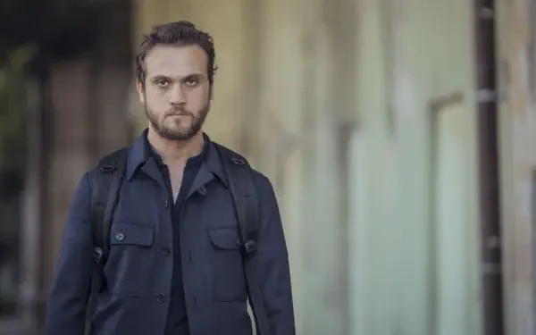 A character from the TV show The Pit is captured in a contemplative moment, standing confidently with a backpack against an urban background. This stunning 4K Ultra HD wallpaper showcases intense detail.