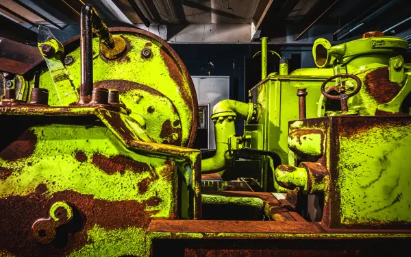Detailed view of rusty machinery, featuring vibrant green and orange hues, creating a striking contrast. A captivating 4K Ultra HD desktop wallpaper that showcases industrial aesthetics.