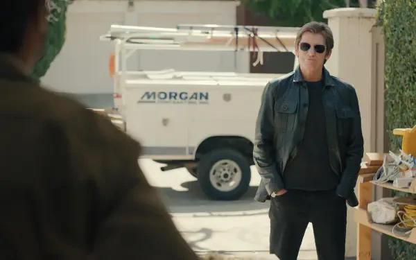 Denis Leary stands confidently in a leather jacket, set against a backdrop featuring a work vehicle, from the TV show No Good Deed (2024). A captivating 4K Ultra HD wallpaper.