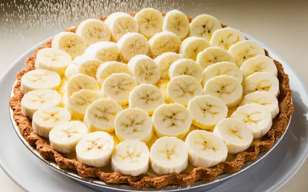 A luscious banana cream pie topped with perfectly sliced bananas, set against a soft background, creates a delightful 4K Ultra HD PC desktop wallpaper and background.