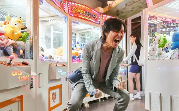 A dynamic scene from the TV show Squid Game featuring Lee Jung-jae, passionately expressing intense emotion amid a vibrant arcade setting. 4K Ultra HD wallpaper.