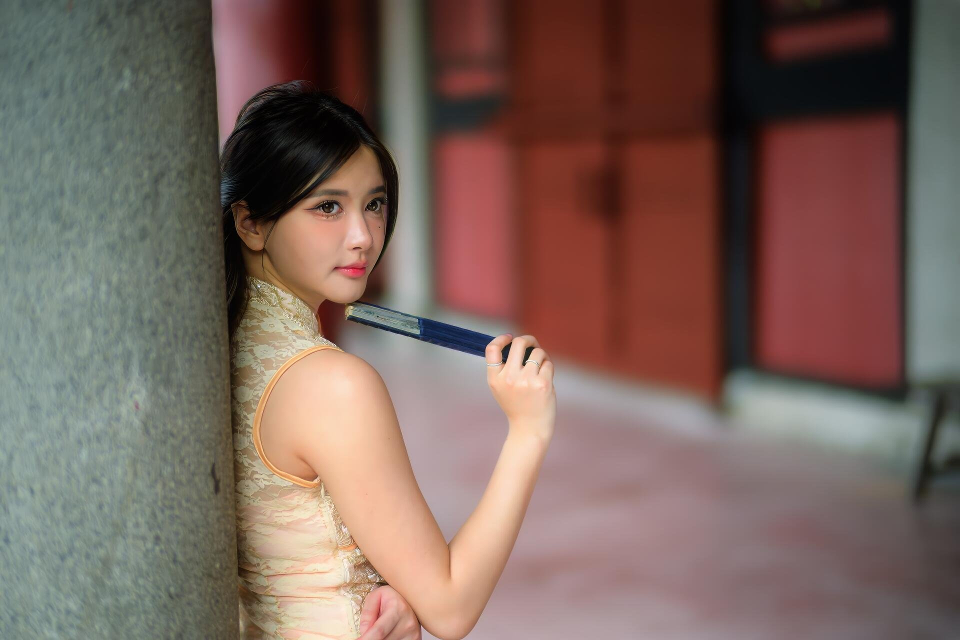 8K Ultra HD PC desktop wallpaper: young woman in a cheongsam leaning against a pillar, holding a book near her shoulder, soft-focus corridor background.