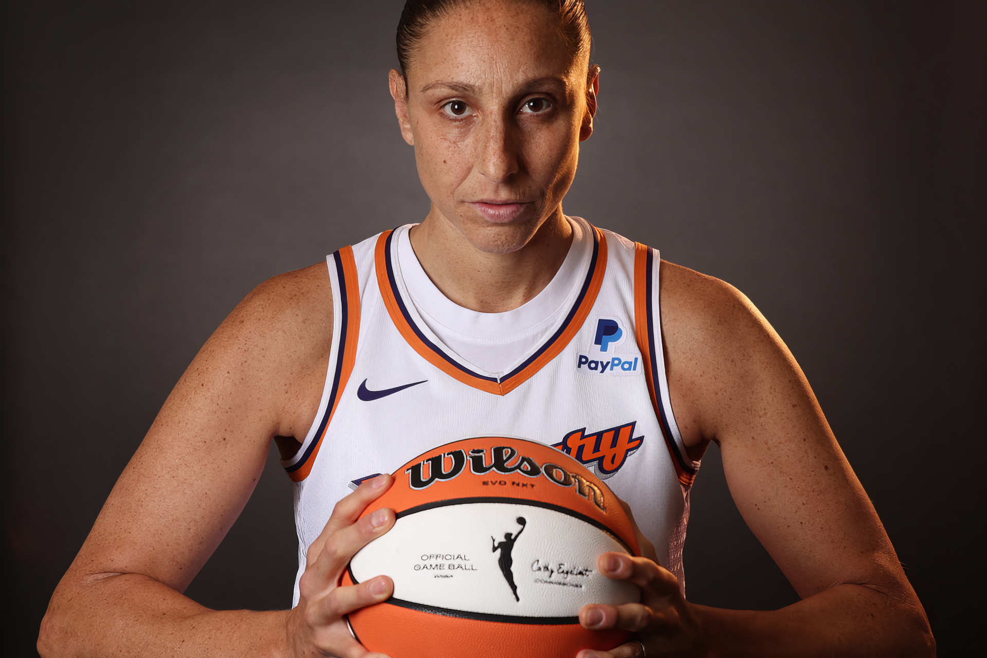 Diana Taurasi, a key player for the Phoenix Mercury, poses confidently with a Wilson basketball, showcasing her strong presence in WNBA sports. HD desktop wallpaper.