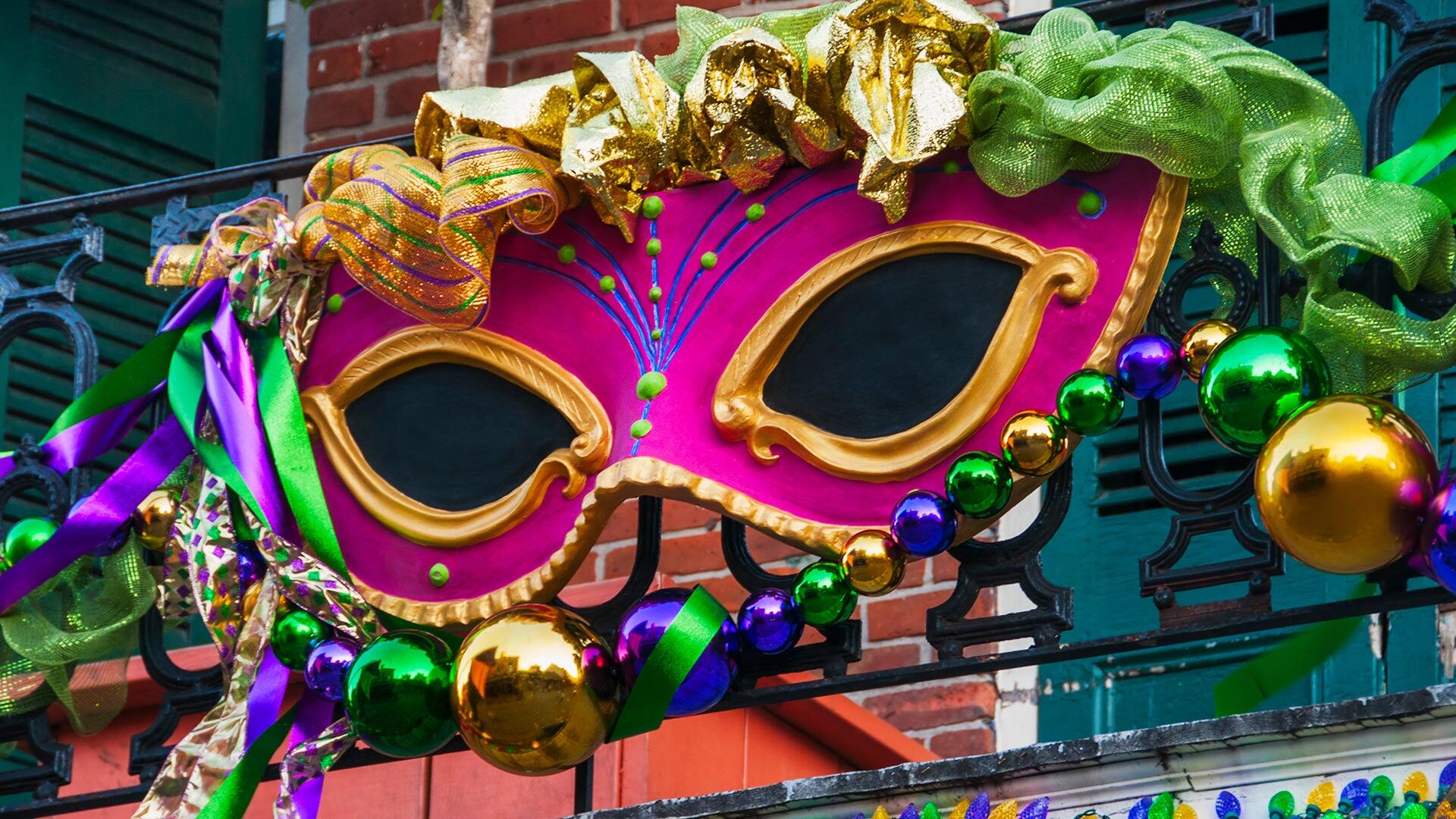 A vibrant Mardi Gras mask adorned with colorful decorations, set against a brick backdrop, brightens this HD desktop wallpaper, capturing the festive spirit of the celebration.