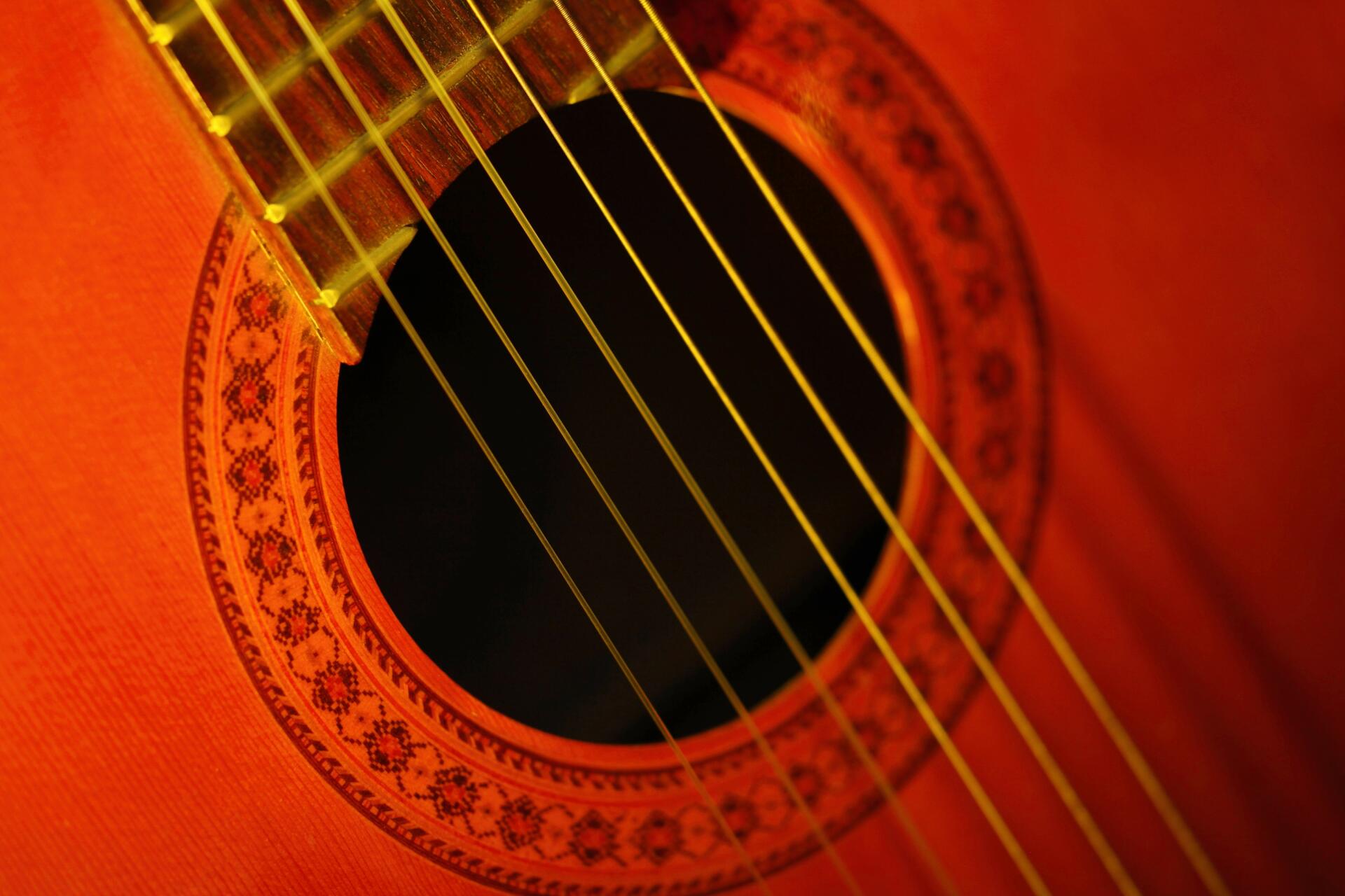 Close-up HD PC desktop wallpaper of a red acoustic guitar: soundhole, rosette and strings highlighted as a musical instrument and music-themed background.