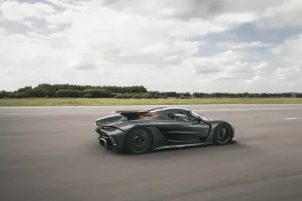 A sleek Koenigsegg Jesko Absolut accelerates on an open road under a partly cloudy sky, captured in stunning 8K Ultra HD quality for an immersive desktop wallpaper experience.