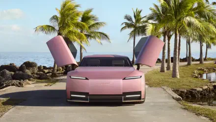 A pink Jaguar Type 00 sports car with butterfly doors open, parked on a palm-lined coastal road, captured in 8K Ultra HD as a PC desktop wallpaper.