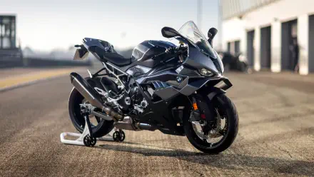 Black BMW S1000RR sports bike on a racetrack pit lane, shot in crisp 4K Ultra HD as a PC desktop wallpaper/background.