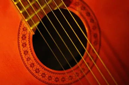 Close-up HD PC desktop wallpaper of a red acoustic guitar: soundhole, rosette and strings highlighted as a musical instrument and music-themed background.