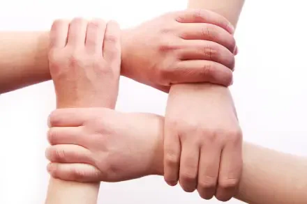 HD PC desktop wallpaper/background of four hands grasping wrists in a square, showing people united—family and team together.