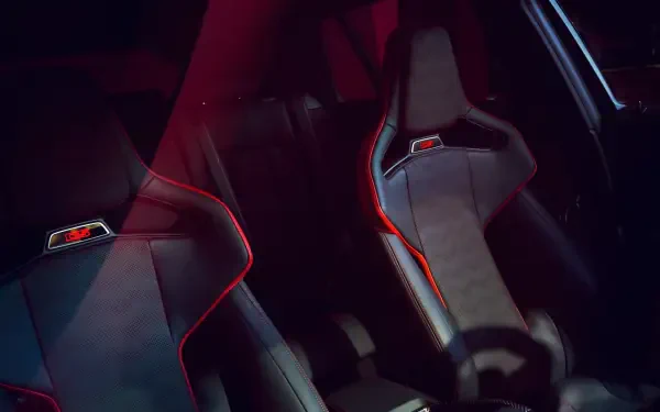 Close-up of the BMW M3 CS Touring's sleek interior, featuring stylish sports seats with striking red accents, set against a dramatic lighting backdrop. High-definition wallpaper.