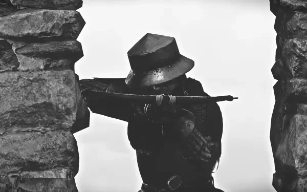 An archer poised with a bow, framed by a stone wall, from Kingdom Come: Deliverance II, depicted in striking black and white. This HD wallpaper captures a moment of tension and focus.